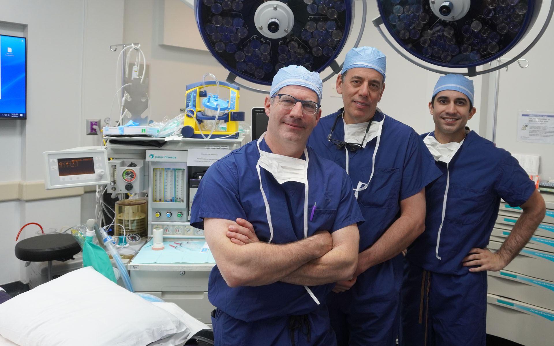 three surgeons smiling in operating room
